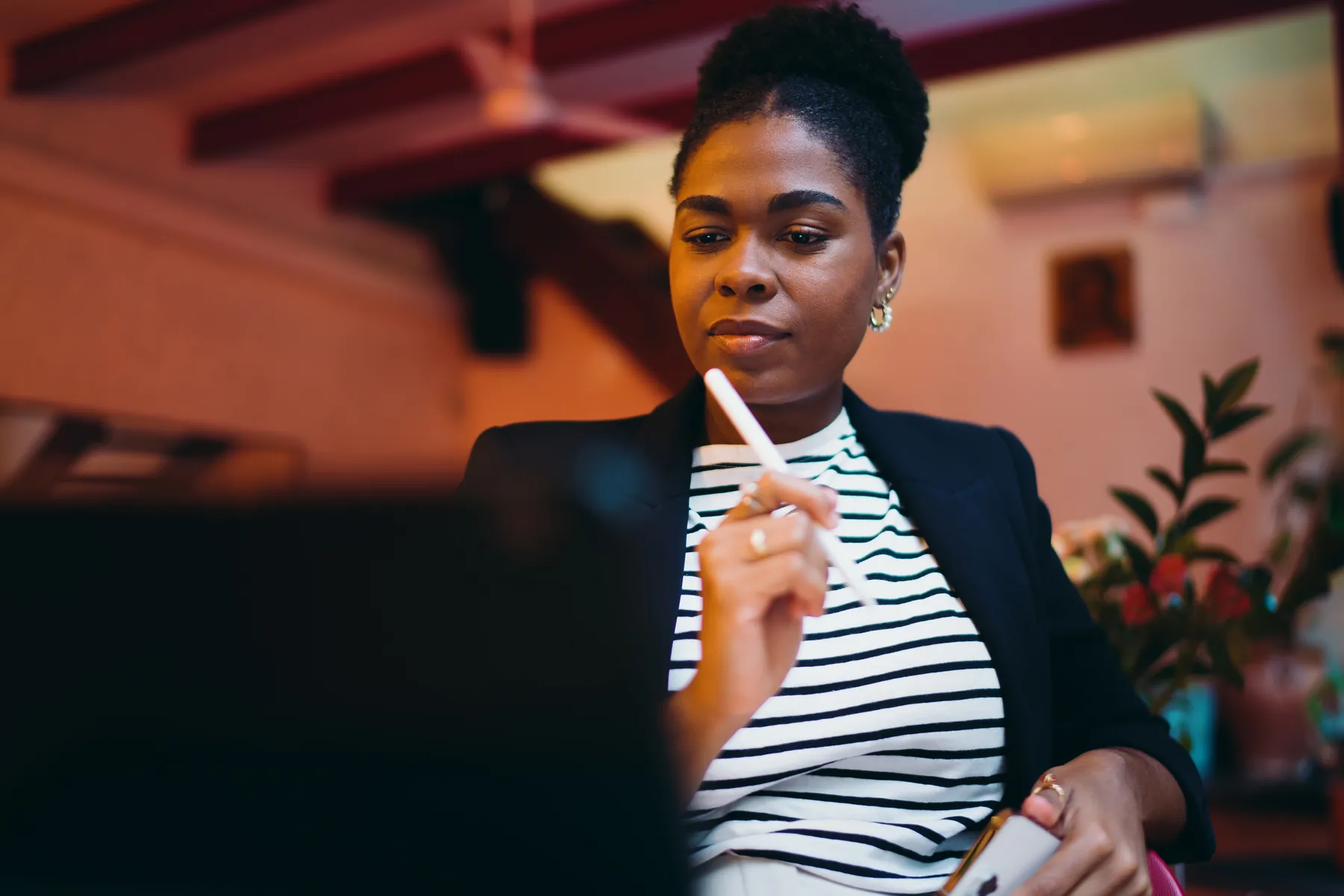 A person pausing to think while holding a pen